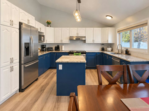 Full kitchen viewed from the dining area, showing the island, refrigerator, cabinets and cooking area.
