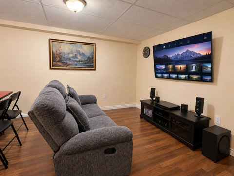 Basement TV lounge adjoining the games area, with the reclining sofa shown upright. This is separate from the two main-floor living rooms.