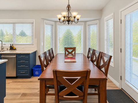 Main-floor dining area with a full-size dining table beside the kitchen and bay windows.