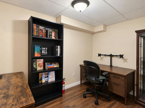 Separate basement office with desk, office chair and bookcase.
