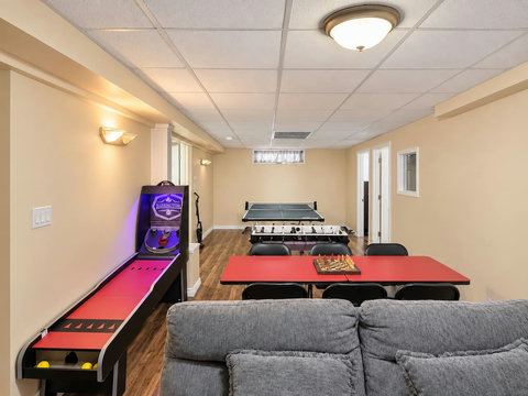 Reverse view of the basement entertainment area, showing the ball-toss game and games tables.