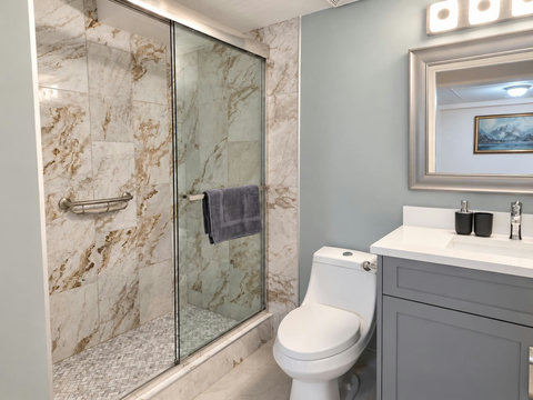 Basement full bathroom with a glass shower, vanity and toilet.