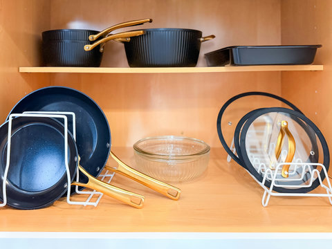 Cookware for every meal — non-stick pans with gold handles, pots, baking pan, and mixing bowls, all neatly organized.