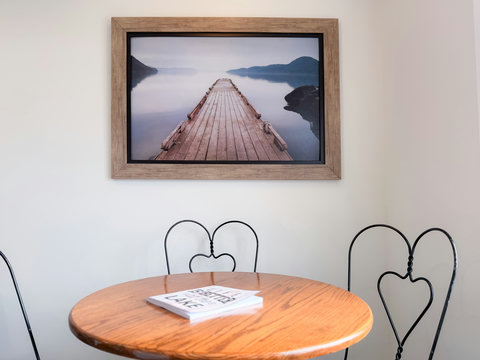 Cozy dining nook with a view. Warm bistro set with a serene framed lake artwork.