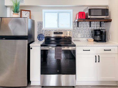 Full kitchen with GE electric range, full-size fridge, microwave, toaster, and dual-brew Keurig — everything you need for a home-cooked meal or quick bite.