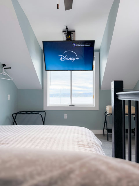 What a view to wake up to! Catch morning lake views, or a late night show — ceiling-mounted remote control mount with a Roku TV viewable right from bed. Your subscriptions (Disney not installed)