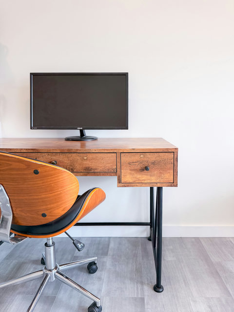 Dedicated workspace with solid wood desk, large monitor, and an iconic mid-century style chair — remote work has never felt this good.