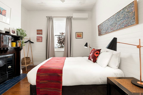 Main queen bedroom with books, artwork, and original fireplace