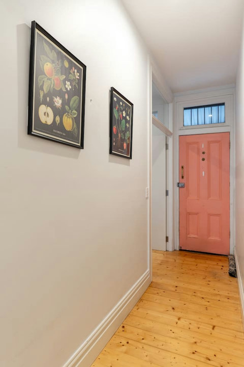 A cheerful coral front door and original timber floors create a warm welcome on arrival.
