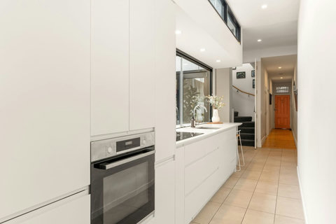 The spacious kitchen offers integrated appliances, abundant cabinetry and a long preparation bench.
