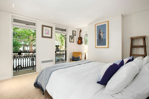 Airy bedroom with balcony access, natural light and leafy neighbourhood views