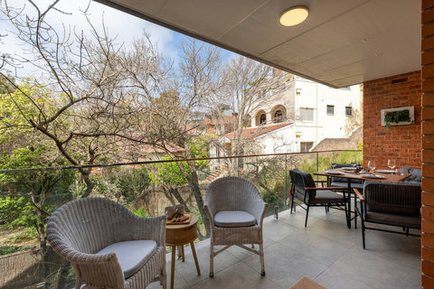Generous covered balcony combining lounge seating and outdoor dining, with leafy views across the neighbourhood