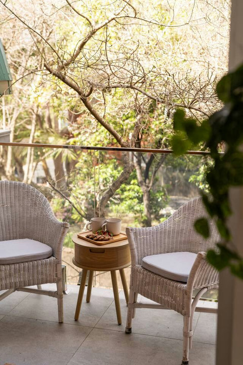 Covered balcony with cushioned seating and a leafy outlook, ideal for a quiet morning coffee