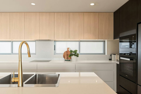 Contemporary kitchen with stone benchtops, streamlined cabinetry and premium integrated appliances