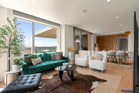 Bright living area with harbour views, statement green sofa and direct access to the terrace
