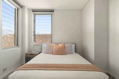Bright queen bedroom with windows on two sides, bringing in plenty of natural light and neighbourhood views