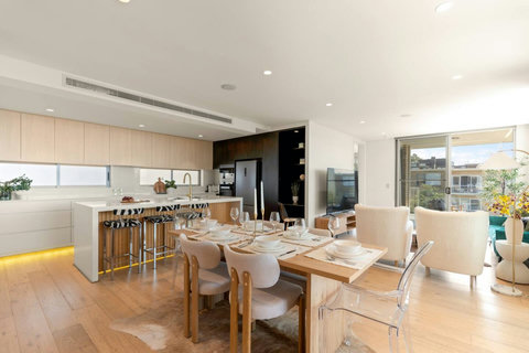 Open-plan dining and kitchen area with warm timber flooring, generous seating and plenty of natural light