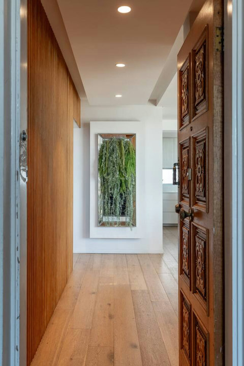 Welcoming entry with a carved timber front door, warm timber finishes and a statement mirror