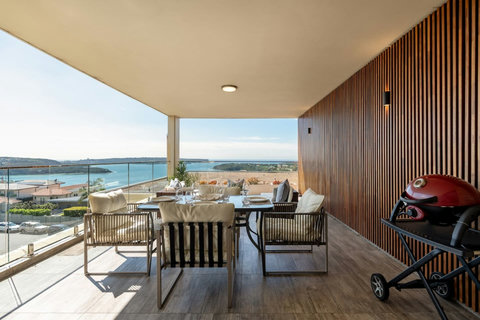 Covered outdoor dining area with harbour views, comfortable seating and a barbecue for easy meals at home