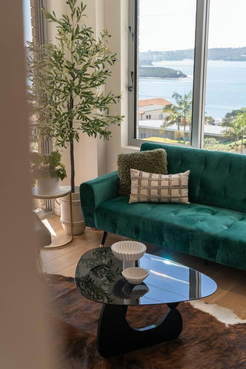 Statement green sofa creates a cosy sitting area beside the windows and leafy indoor planting
