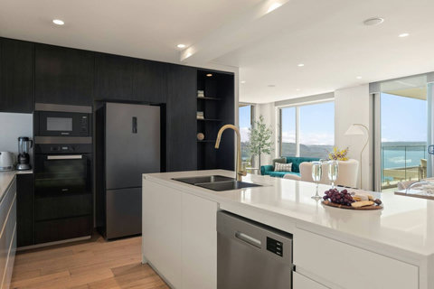 Spacious kitchen with a large island, dishwasher and an open outlook towards the harbour-facing living space