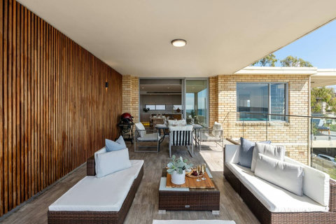 Covered terrace with generous outdoor lounge seating, warm timber detailing and an easy connection back into the apartment