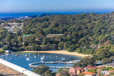 Leafy harbour outlook with a sheltered beach and marina below, framed by Sydney’s coastal landscape