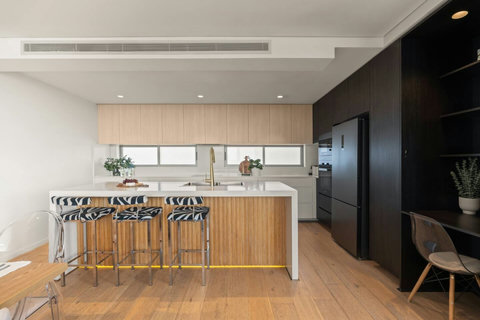 Contemporary kitchen with a large island, breakfast-bar seating, stone benchtops and streamlined cabinetry