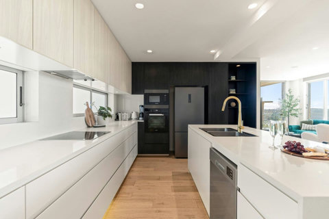 Sleek galley-style kitchen with extensive storage, integrated appliances and a bright connection to the living area