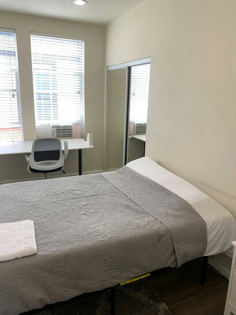 Queen sized bed, freshly cleaned linens, and a desk with desk chair.