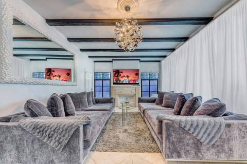 Living room with oversized custom-made designer sofas made in California with designer pillows and an 86-inch smart TV for the movie theater entertainment experience. Netflix and Amazon movies are included. 