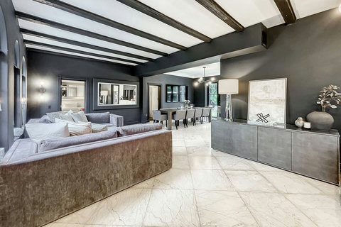 A modern living room with marble floors and a comfortable sofa next to a clean, stylish dining area.