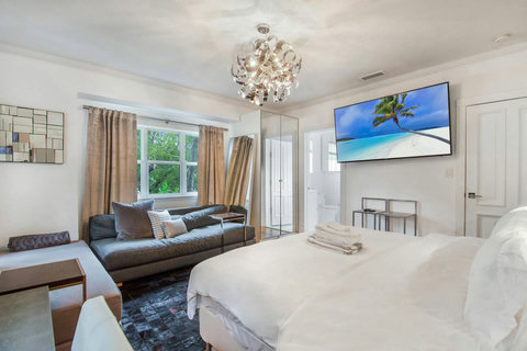 An elegantly designer bedroom boasting a luxurious KING-size beds (or 2 twin beds upon request), a sleek professional workspace, designer sofa daybed, and closet, multiple windows that create a bright, open, and sophisticated atmosphere.
