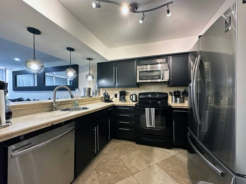 Sleek Modern Kitchen with Dine-in Bar & Stainless Steel Appliances: Experience culinary delight in this spacious kitchen. Your perfect blend of style and functionality!
