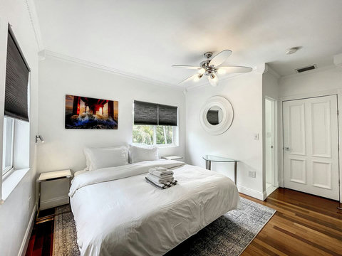 An elegantly spacious designer bedroom boasting two luxurious KING-size beds, a sleek professional workspace, and multiple mirrored closets that create a bright, open, and sophisticated atmosphere.