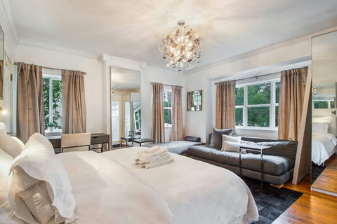 An elegantly designer bedroom boasting a luxurious KING-size beds (or 2 twin beds upon request), private balcony overlooking pool area, a sleek professional workspace, and mirrored closets that create a bright, open, and sophisticated atmosphere.