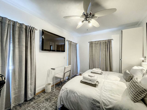 An elegantly designer bedroom boasting a luxurious KING-size beds (or 2 twin beds upon request), private balcony overlooking pool area, a sleek professional workspace, and mirrored closets that create a bright, open, and sophisticated atmosphere.