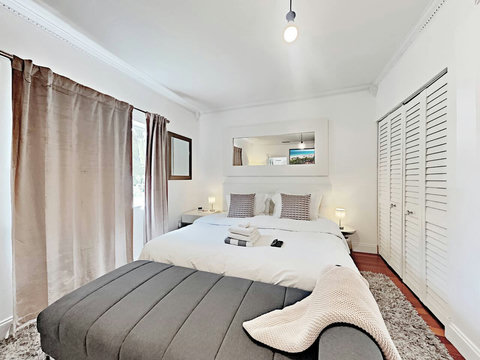 An elegantly designer bedroom boasting a luxurious KING-size beds (or 2 twin beds upon request), a sleek professional workspace, and closet, window that create a bright, open, and sophisticated atmosphere.
