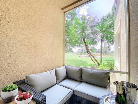 Relax and unwind in this stunning outdoor living room patio with a wall-mounted TV, offering picturesque views of the PGA Clubhouse and Learning Center.

