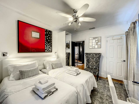 An elegantly designer bedroom boasting a luxurious KING-size beds (or 2 twin beds upon request), private balcony overlooking pool area, a sleek professional workspace, and mirrored closets that create a bright, open, and sophisticated atmosphere.