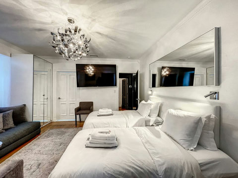 An elegantly designer bedroom boasting a luxurious KING-size beds (or 2 twin beds upon request), a sleek professional workspace, and closet, window that create a bright, open, and sophisticated atmosphere.