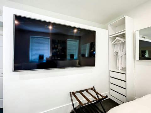 Luxurious Bedroom Retreat - Indulge in comfort with a 70-inch Smart TV, memory foam mattresses, cozy dimmer lighting, USB chargers, and stylish designer mirrors.