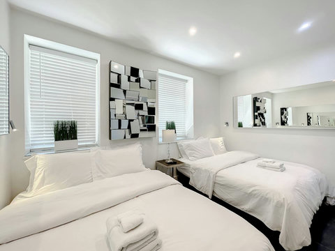 Luxurious Bedroom Retreat - Indulge in comfort with a 70-inch Smart TV, memory foam mattresses, cozy dimmer lighting, USB chargers, and stylish designer mirrors.