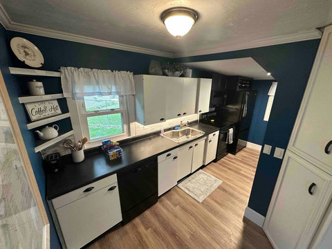 The galley-style kitchen features black appliances, including dishwasher. The kitchen was updated in 2021 and features a large single basin sink with racks and pull-out sprayer.