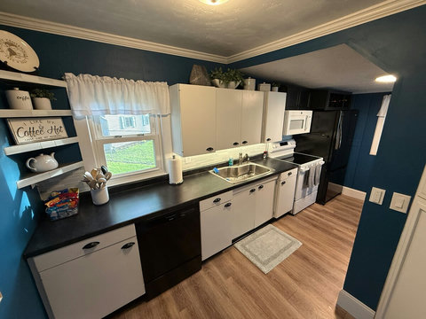 The kitchen includes bottom freezer fridge with ice maker, electric range, over-the-range microwave, and dishwasher. Countertop features a large single basin sink with racks and pull-out sprayer. Cookware, dishes, bowls, small appliances and more!