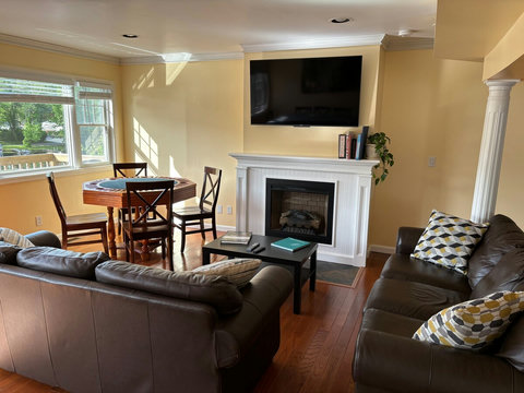 Living room with 2 sofas, Electric fireplace, 55-Inch ULED 4K UHD Google TV, and game table.