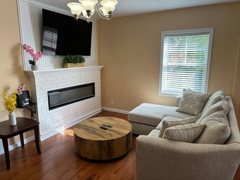 Living room in 2nd floor with modern electric fireplace, coffee table, sleeper sofa, and 65-Inch ULED 4K Google TV to enjoy movies in the large screen.