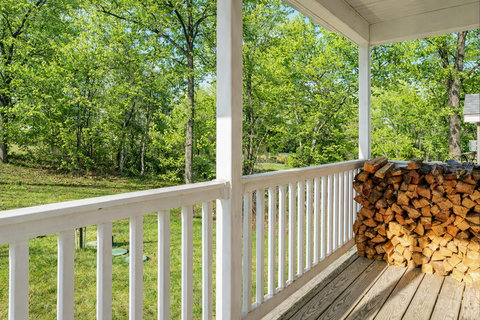 Covered porch with forest views and stacked firewood—peaceful retreat