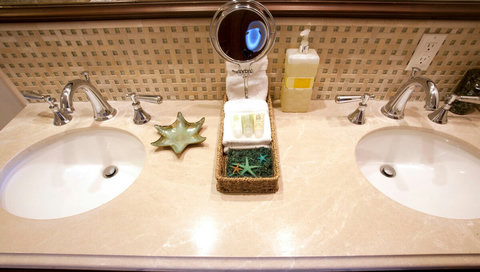 - Clean, spacious double vanity with polished stone and modern chrome fixtures
- Thoughtful welcome basket includes plush towels, toiletries, and starfish accents
- Mosaic tile backsplash and ambient lighting complete the spa like setting