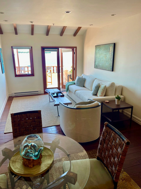 - Open concept layout connects cozy seating with a stylish dining nook & balcony views
- Natural light floods through French doors, complemented by vaulted ceilings & beam accents
- Artisan decor and rich wood tones bring warmth to every corner